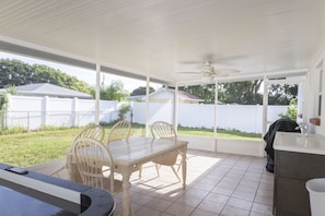 A covered patio with a table and chairs, a ceiling fan, and a view of the backyard.