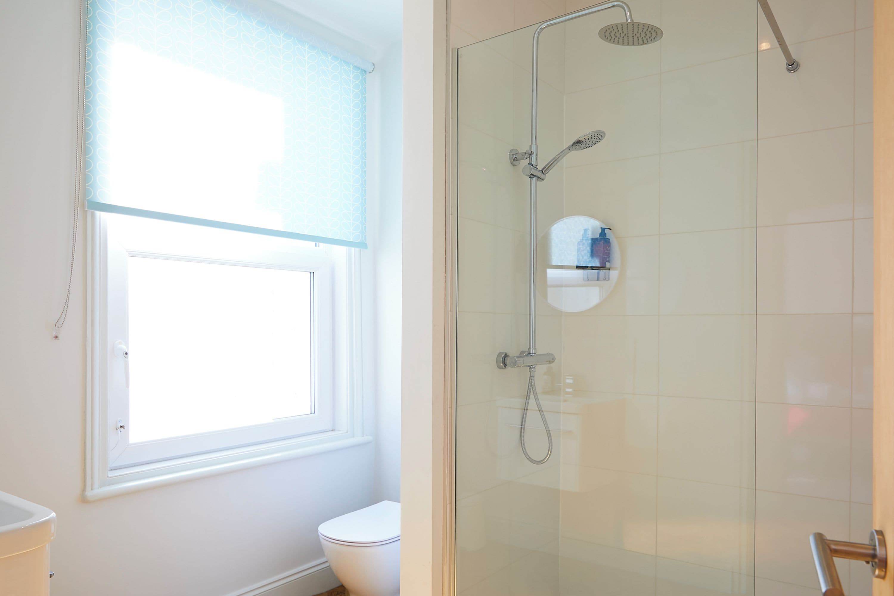 A bathroom with a toilet, a window, and a glass-enclosed shower area.