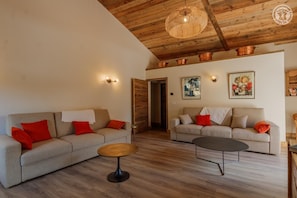 Un salon moderne avec deux canapés, une table basse et un plafond en bois.
