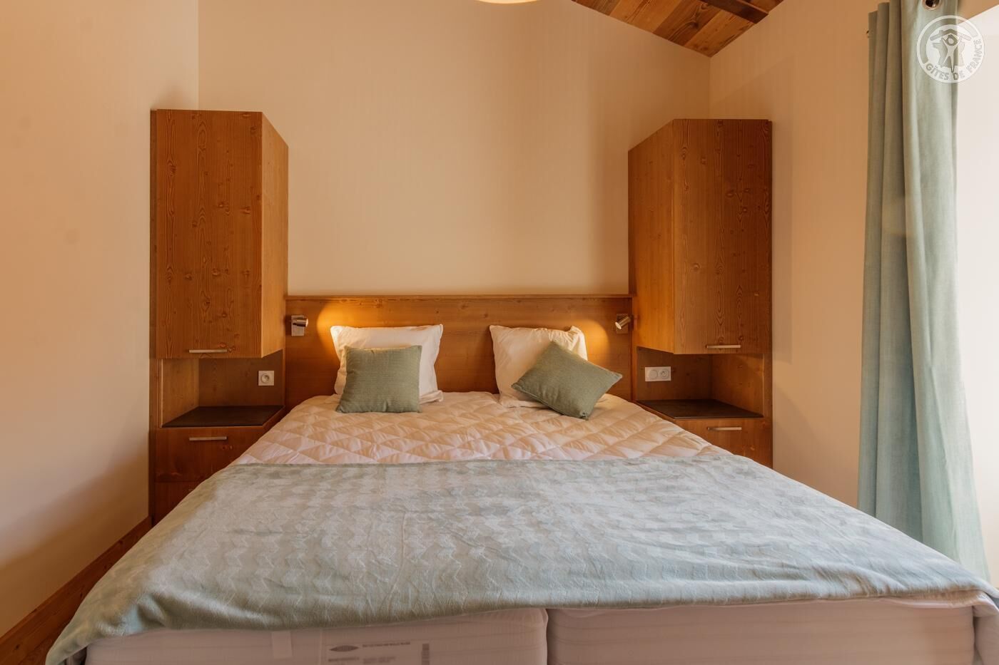 A bedroom with a wooden headboard, two bedside tables, and a bed with a quilted blanket.