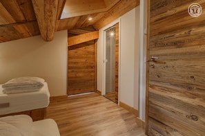 Ein Zimmer mit Holzboden, einer Holztür und einem Bett mit weißer Decke.
