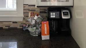 A kitchen with a coffee maker, a cabinet with mugs, and a bag of Dunkin' coffee. - Beautiful Lakefront home - perfect getaway for every season!   (Ashburnham)