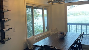 A dining area with a wooden table, chairs, a chandelier, and wine bottles on a rack. - Beautiful Lakefront home - perfect getaway for every season!   (Ashburnham)