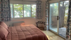 A bedroom with a bed, a radiator, a window with curtains, and a sliding glass door leading to an outdoor area. - Beautiful Lakefront home - perfect getaway for every season!   (Ashburnham)