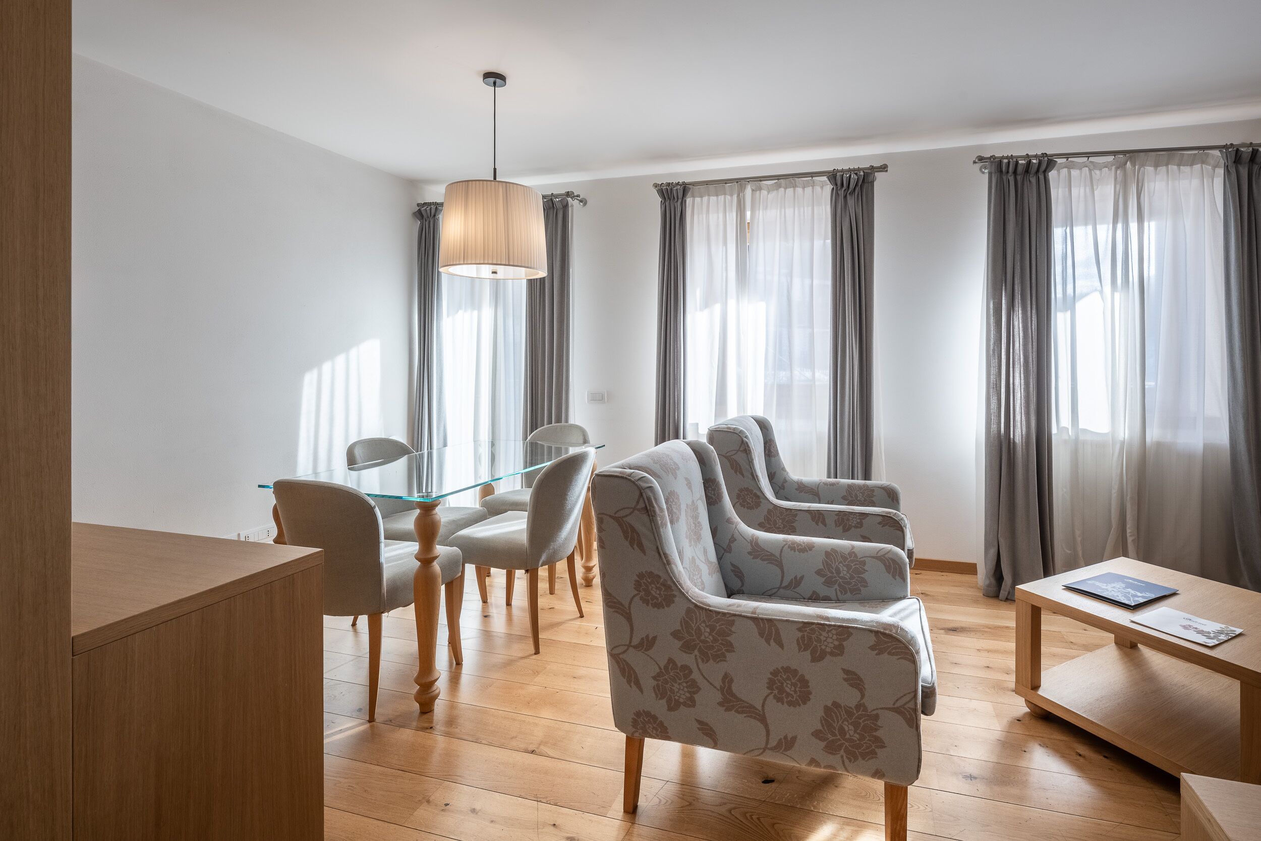 Una sala de estar moderna con piso de madera, una mesa de comedor de vidrio y un conjunto de sofá.