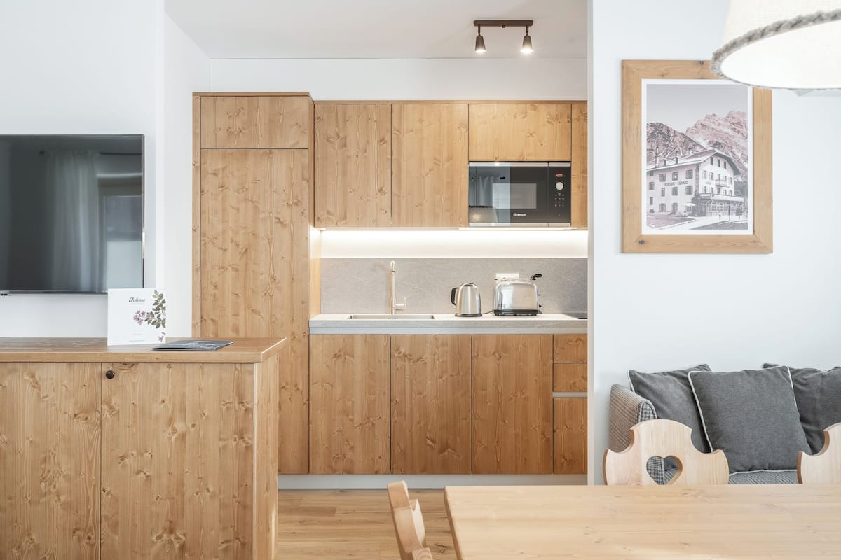 A modern kitchen with wooden cabinets, a built-in microwave, and a dining area with a wooden table and chairs.