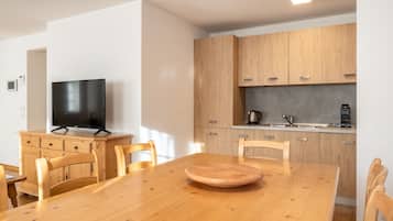 A modern kitchen with wooden cabinets, a built-in oven, and a coffee machine.