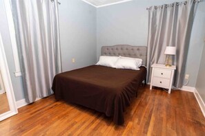 Cozy retreat with a neatly made bed, light blue walls, and a wooden floor.