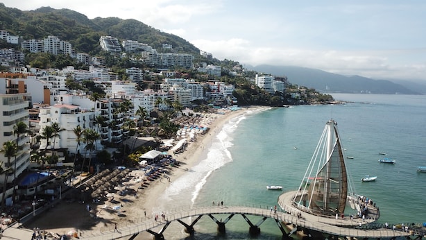A coastal cityscape with a prominent bridge, beachfront, and residential buildings.