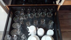 Un tiroir contenant divers objets en verre, notamment plusieurs verres à vin et des bols blancs.