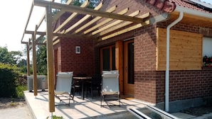 Un espace patio agrémenté d’une pergola en bois, de deux chaises, d’une table et d’une plante en pot.