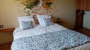 Une chambre à coucher avec un lit, des oreillers, une table de chevet, une armoire en bois et une fresque murale.