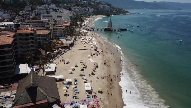 Un paisaje urbano costero con playa, edificios y un puente.