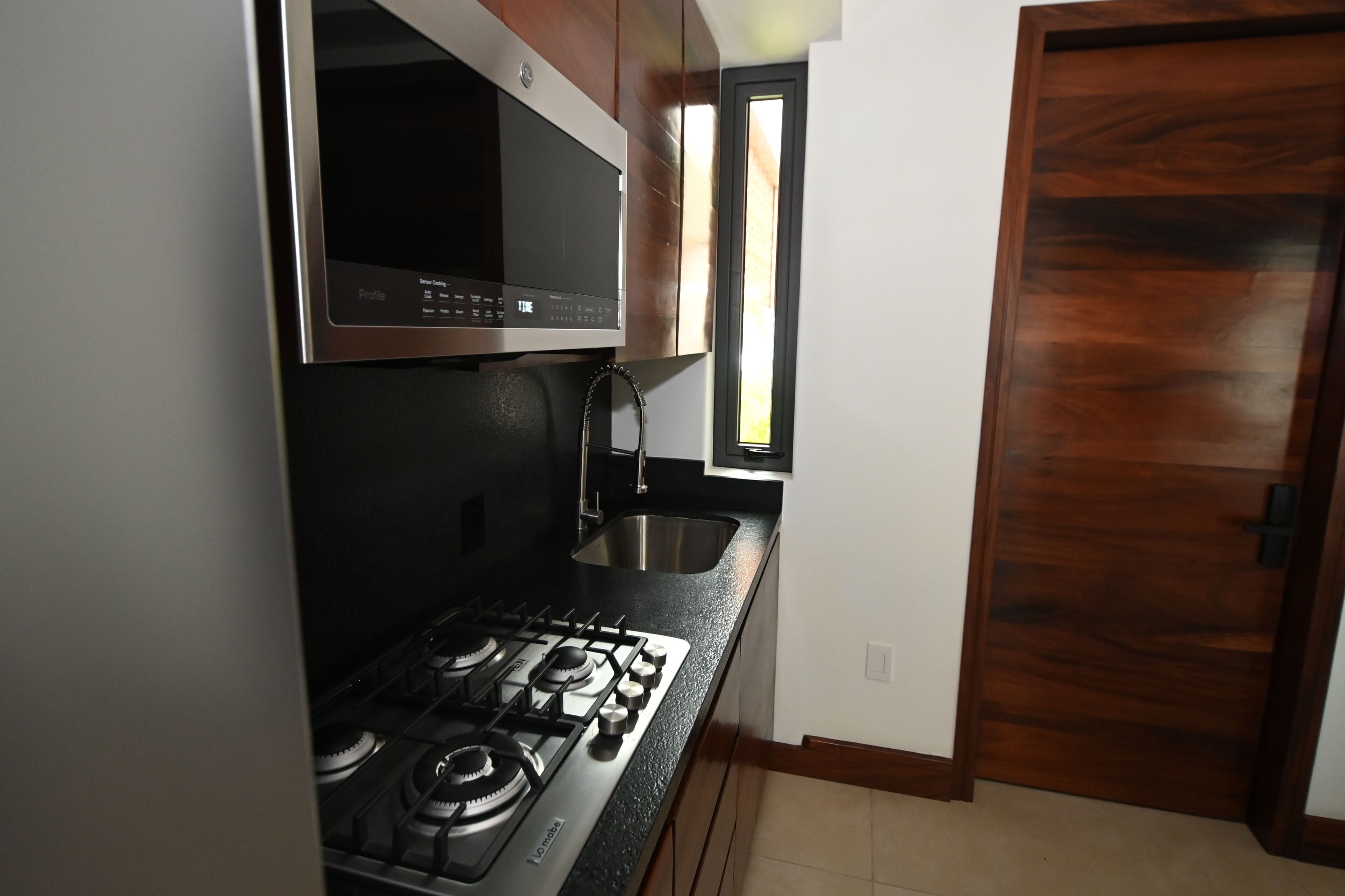 A kitchen with a gas stove, a microwave, and a sink.