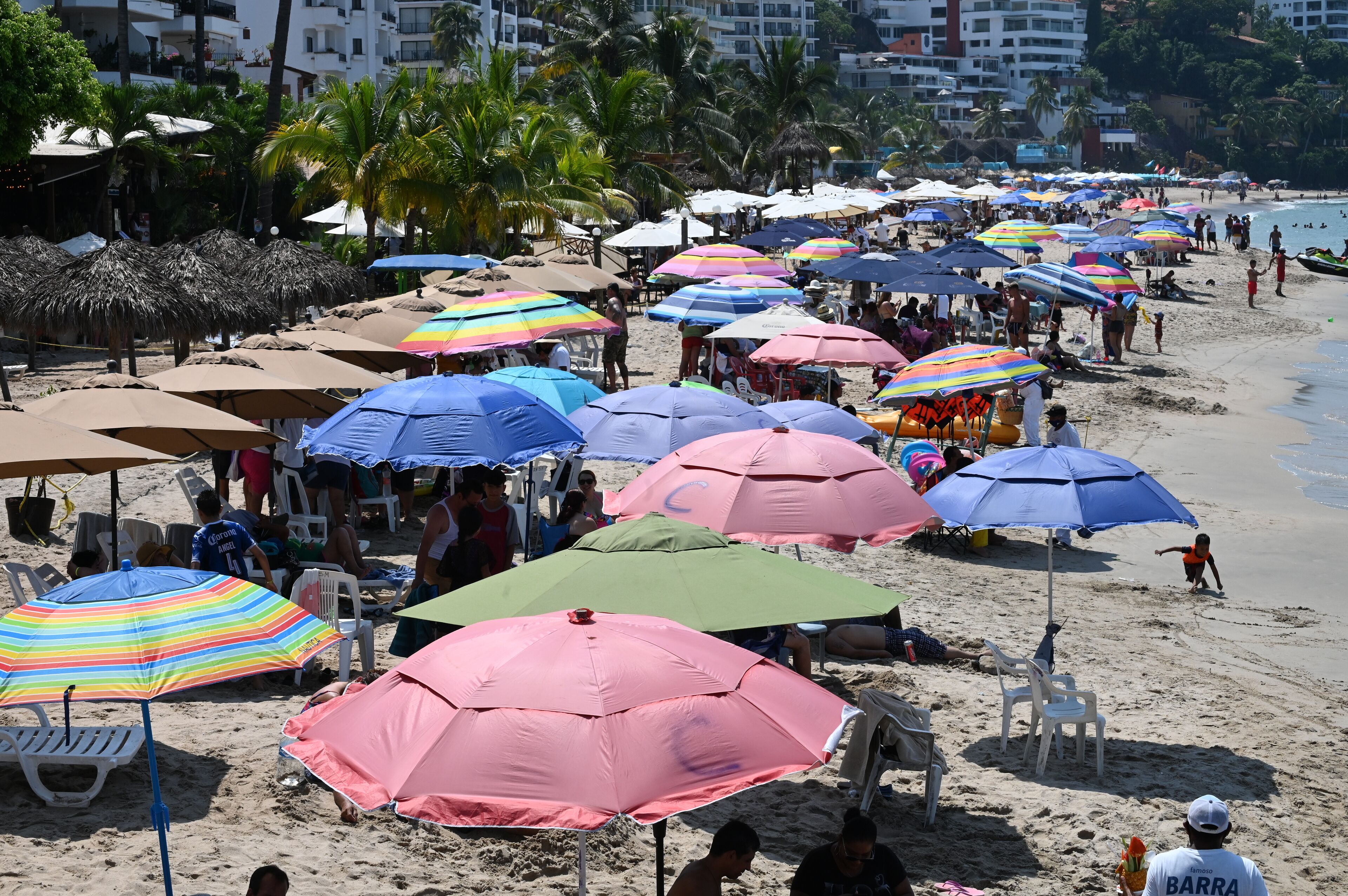 A crowded beach with numerous colorful umbrellas and beach chairs.