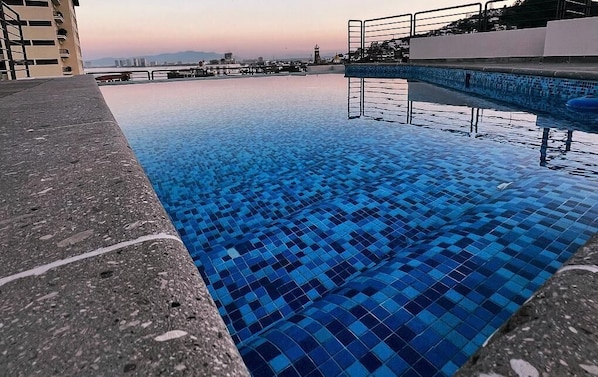 A swimming pool with a tiled edge and a view of buildings in the background.