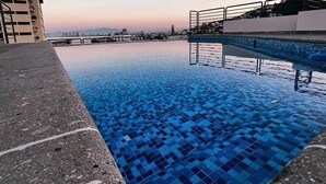 Une piscine dont le bord est revêtu de carrelage, avec une vue sur des bâtiments en arrière-plan.