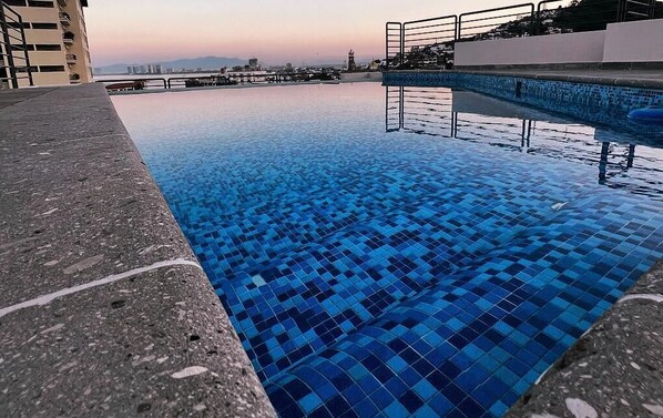 A swimming pool with a tiled edge and a view of buildings in the background.