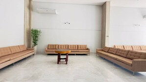 A modern waiting area with a beige sofa, a small wooden table, and a potted plant. - Spazzio diRoma - Cortezia ao Park diRoma (Caldas Novas)
