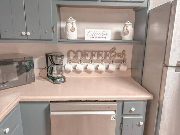 A kitchen with a coffee bar, a microwave, a coffee maker, and a dishwasher.
