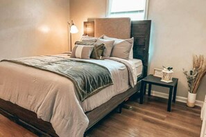 Een slaapkamer met een bed, nachtkastjes, een lamp en een raam.