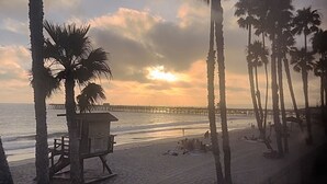 A beach with palm trees, a lifeguard tower, and a pier extending into the water. - Beachfront Paradise 10 steps from the Beach. Heated Pool, Spa, Sauna. No fees (Port Hueneme)