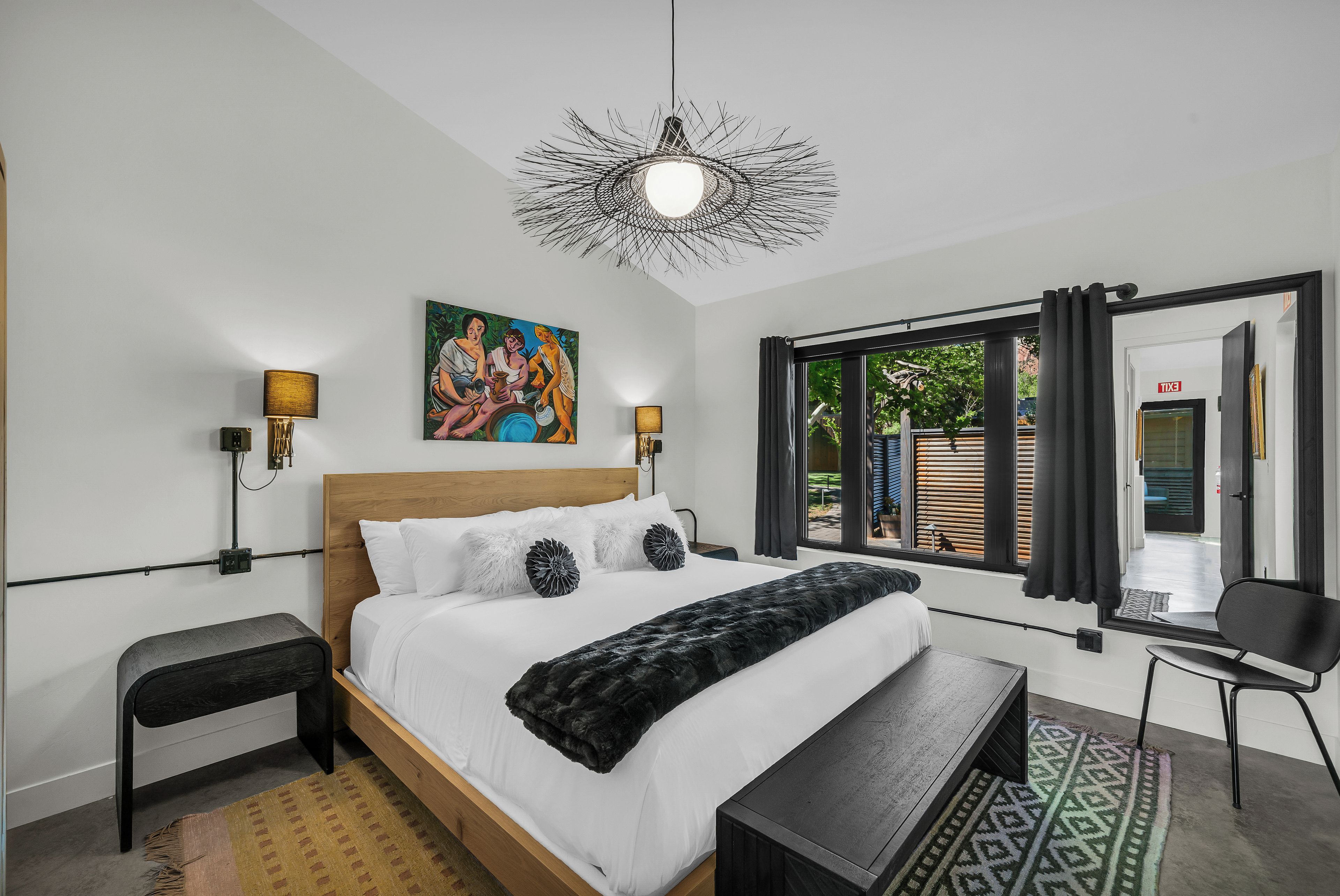 Un dormitorio moderno con una cama de madera, un banco, un escritorio y un cuadro en la pared.