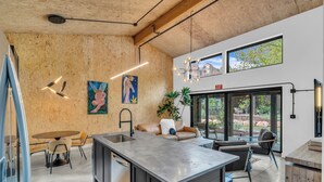 Una cocina moderna con una isla central, paredes de madera y un comedor con mesa y sillas.