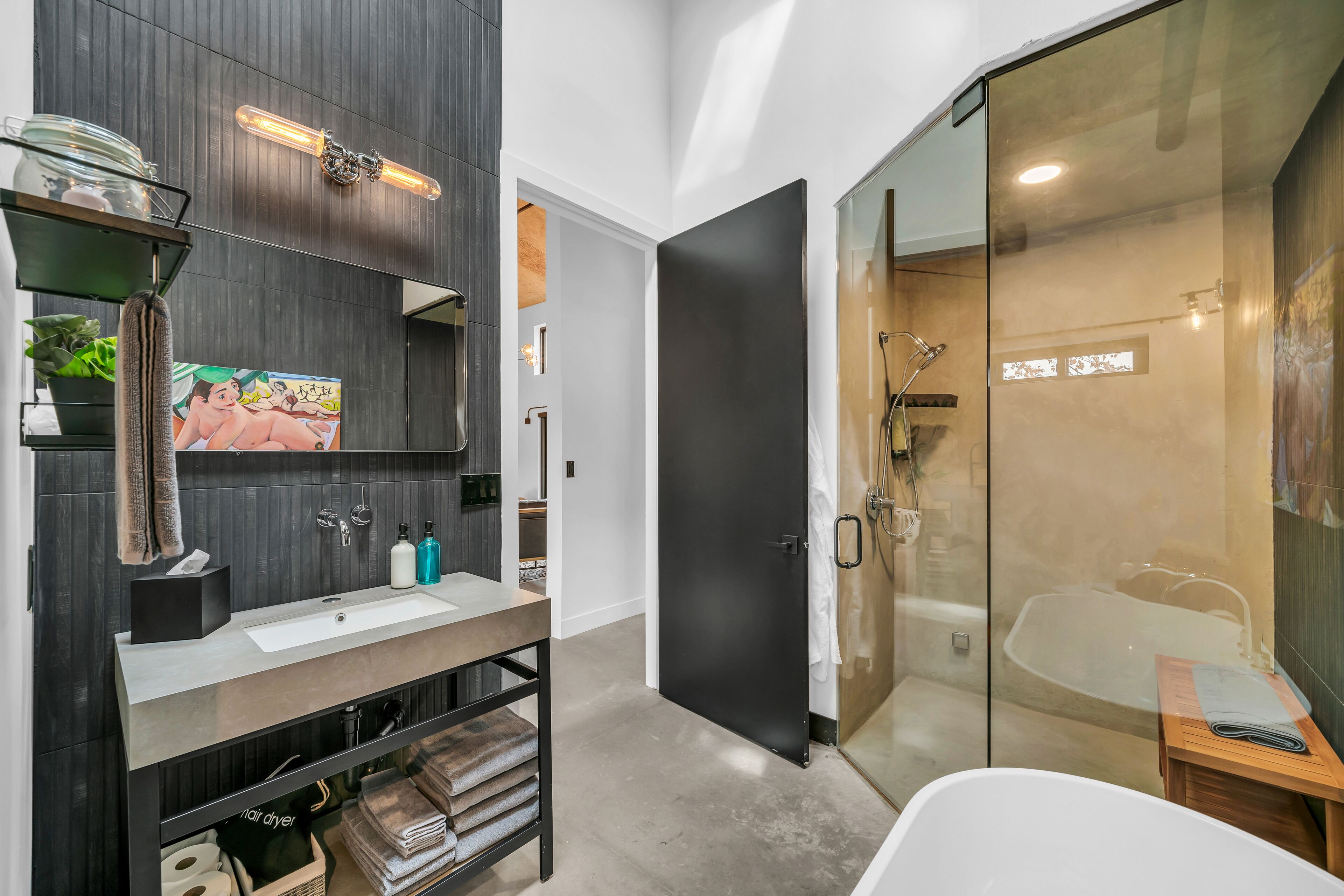 A modern bathroom with a large mirror, a sink, and a glass-enclosed shower area.