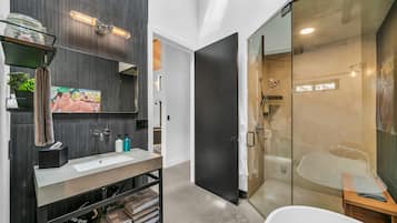 A modern bathroom with a large mirror, a sink, and a glass-enclosed shower area.