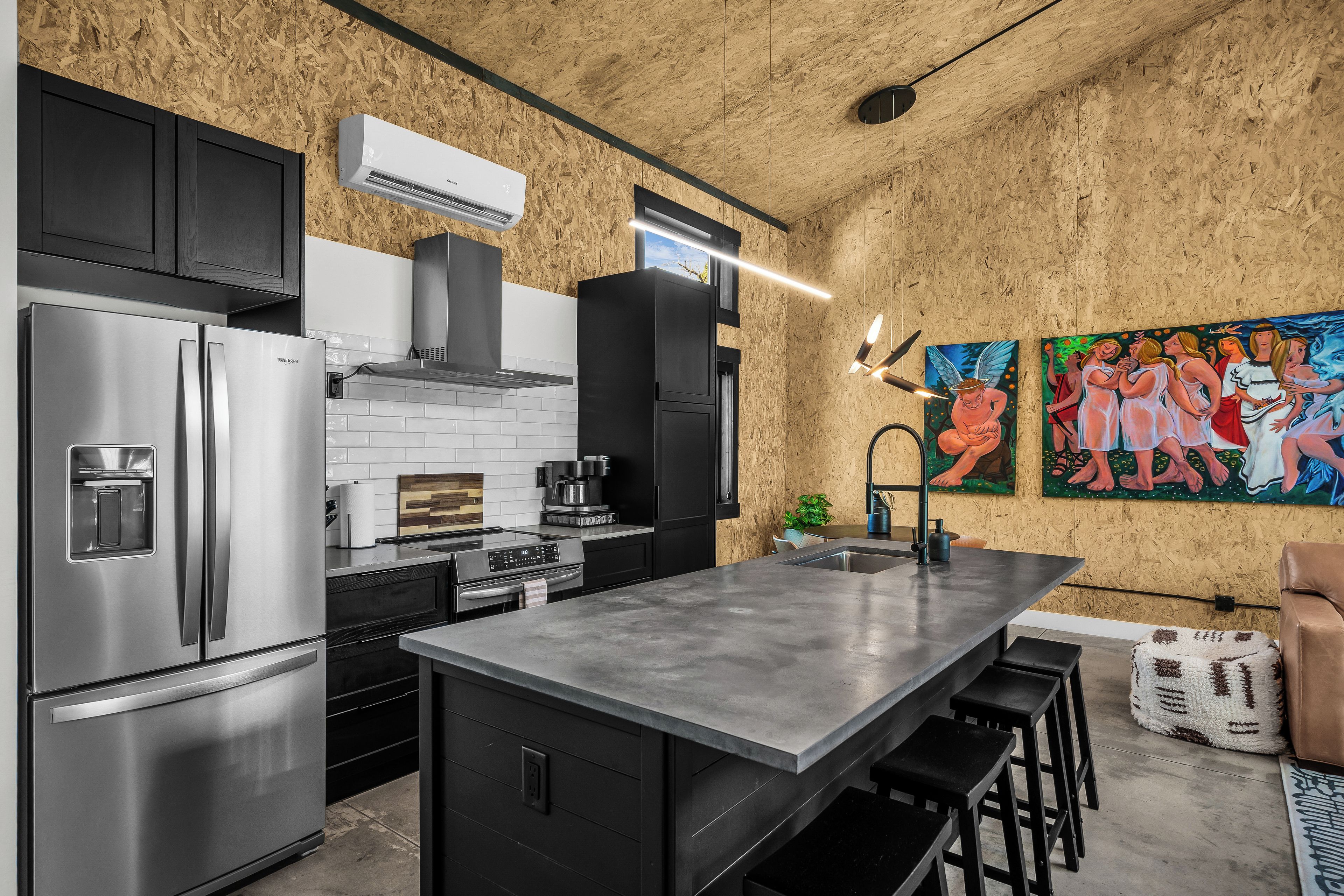 Una cocina moderna con electrodomésticos de acero inoxidable, una isla grande y un cuadro en la pared.