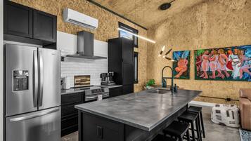 Una cocina moderna con electrodomésticos de acero inoxidable, una isla grande y un cuadro en la pared.