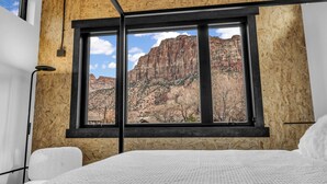 Un dormitorio con un ventanal que ofrece vistas a un paisaje montañoso.