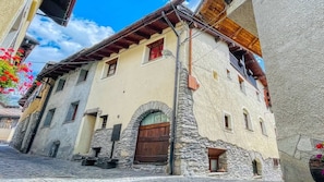 A traditional stone building with a wooden door, arched windows, and a balcony.