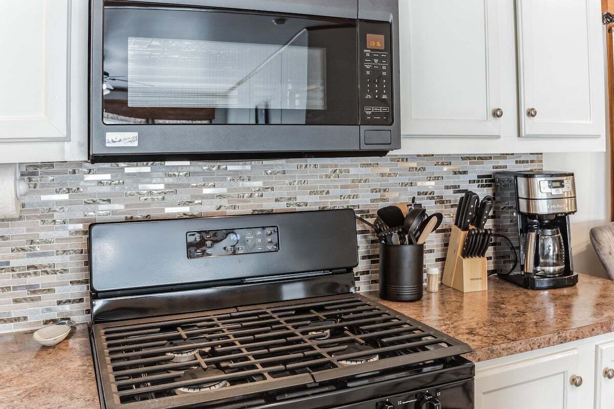 Une cuisine équipée d’une cuisinière en acier inoxydable, d’un four à micro-ondes et d’une machine à café posée sur le plan de travail.