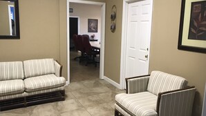 Un salon avec un canapé à rayures, un fauteuil et une porte donnant sur une autre pièce.