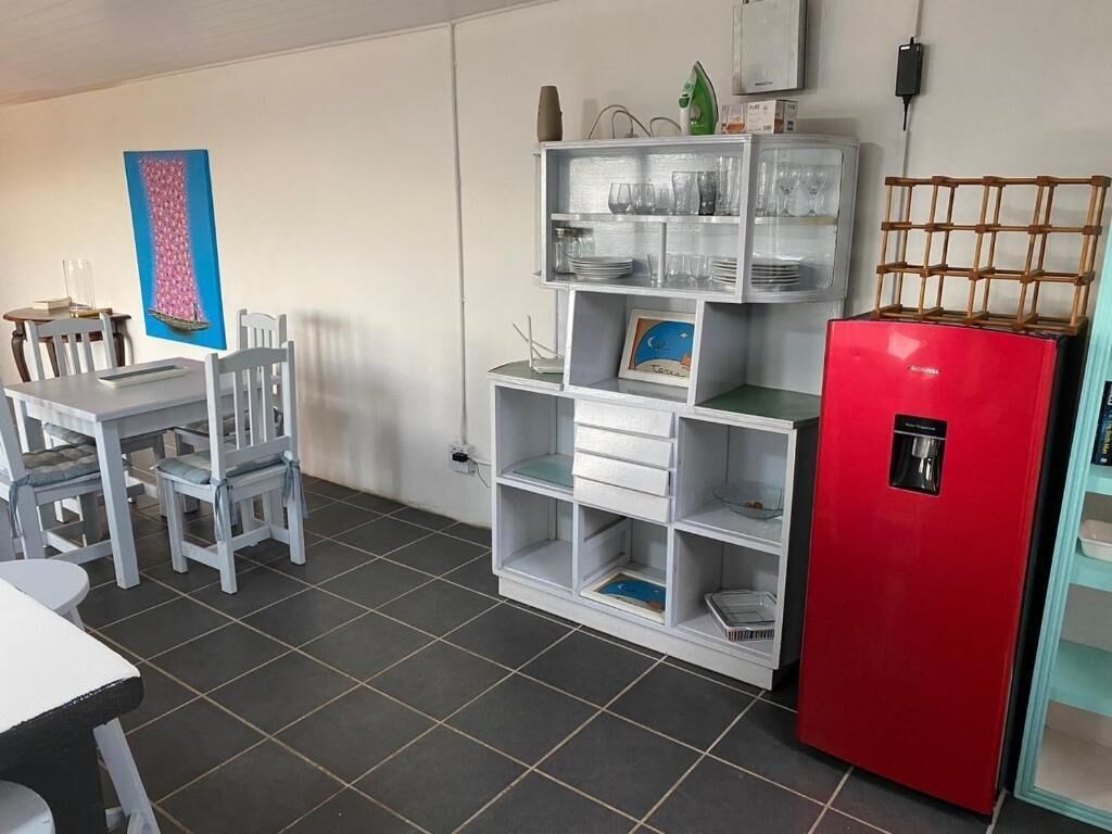 A kitchen with a white cabinet, a red refrigerator, and a dining table with chairs.