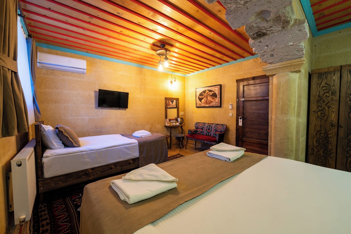 A room with two beds, a small table, a chair, and a door.