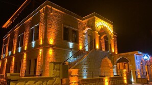 Ein historisches Gebäude mit einer Stein-Fassade, einer zentralen Treppe und einem Schild mit der Aufschrift 'RUSSIAN CAVES HOTEL'.