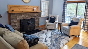 A living room with a stone fireplace, two armchairs, a sofa, and a large window with curtains. - Private Lakehouse Getaway for relaxing and fun! (Weare)