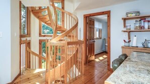 A modern kitchen with a wooden spiral staircase, wooden flooring, and a view of the outdoors. - Private Lakehouse Getaway for relaxing and fun! (Weare)