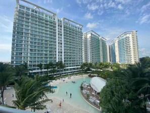 Un hotel de gran altura con varios pisos, un patio central con piscina y palmeras circundantes.