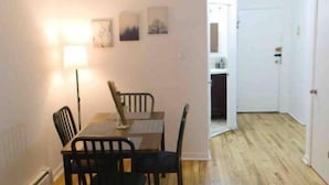 Un coin repas avec une table et des chaises, une lampe et des œuvres d’art accrochées au mur.