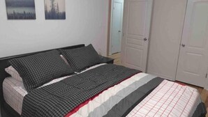 Une chambre à coucher avec un lit, deux tableaux accrochés au mur et une porte.