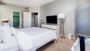 Ett modernt hotellrum med en stor säng, en platt-TV, en sänglampa och en rymlig klädkammare.