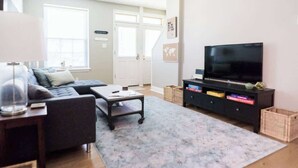 Ett vardagsrum med en soffa, ett soffbord, en tv och en bokhylla.