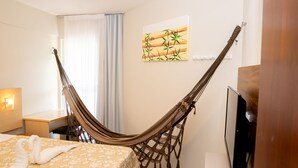 Una habitación con cama, una hamaca, un televisor y un cuadro en la pared.