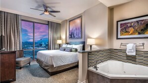 Habitación de hotel con una cama grande, zona de estar, bañera y vistas a la ciudad.