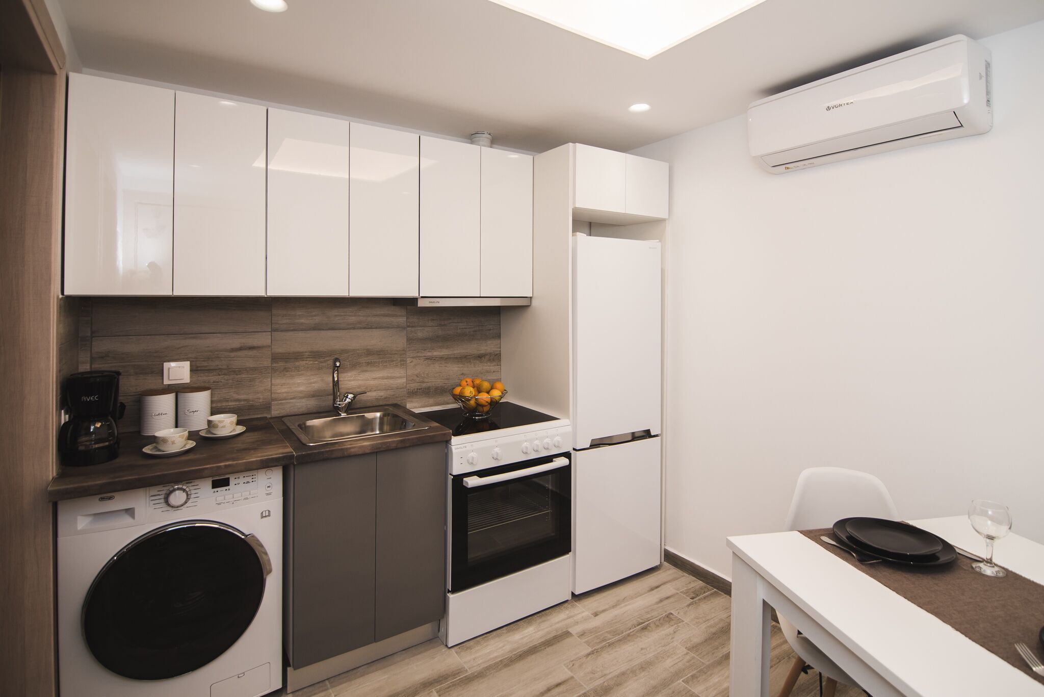 Une cuisine compacte équipée d’un lave-linge, d’un four et d’un évier.