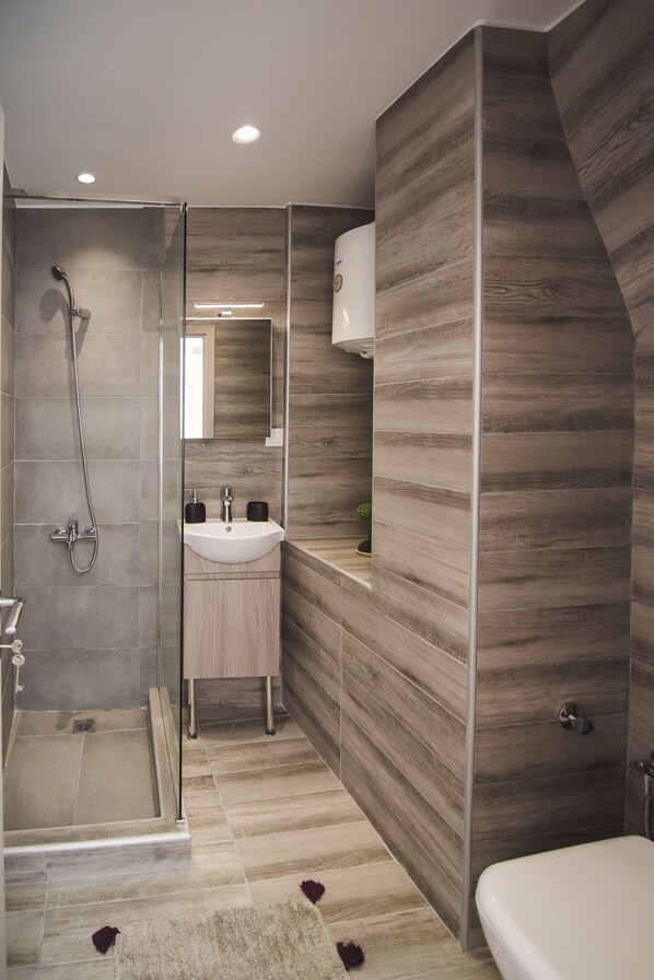 Un baño moderno con ducha de vidrio, lavamanos con espejo y bañera.